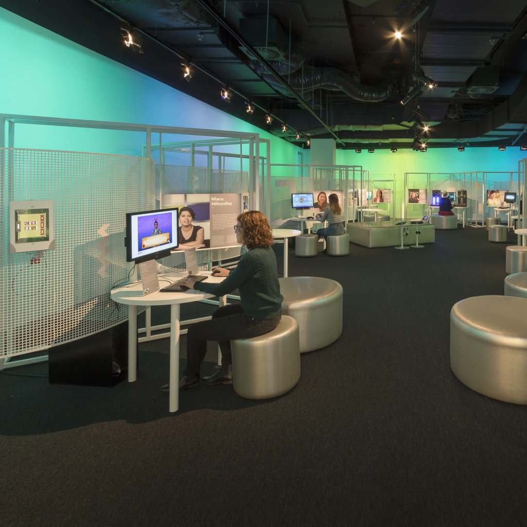 A woman sitting at a computer at the Code Breakers: Women in Games exhibition.
